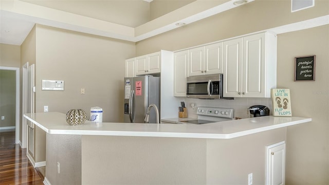 kitchen featuring white cabinetry, dark wood-type flooring, stainless steel appliances, tasteful backsplash, and kitchen peninsula