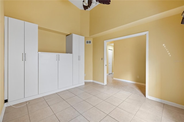 unfurnished bedroom featuring a closet, light tile patterned flooring, and a high ceiling