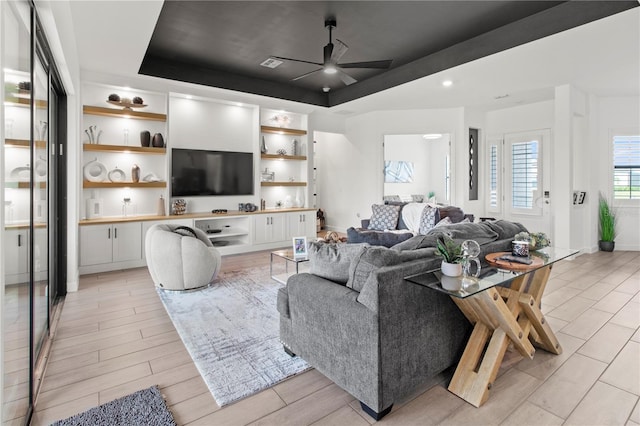 living room with ceiling fan and a tray ceiling