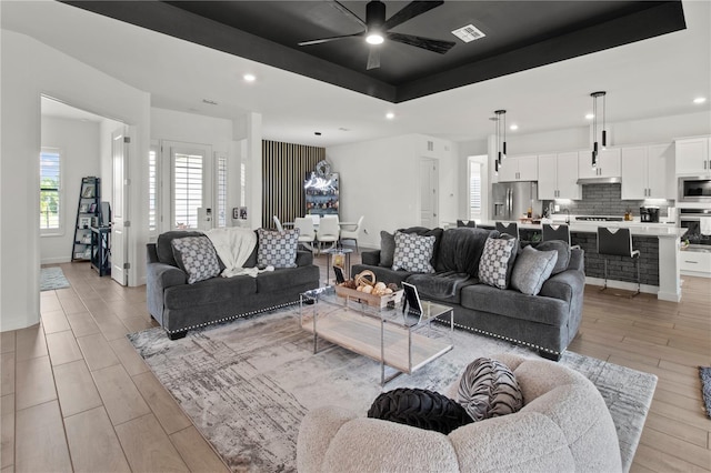 living room with ceiling fan and a raised ceiling