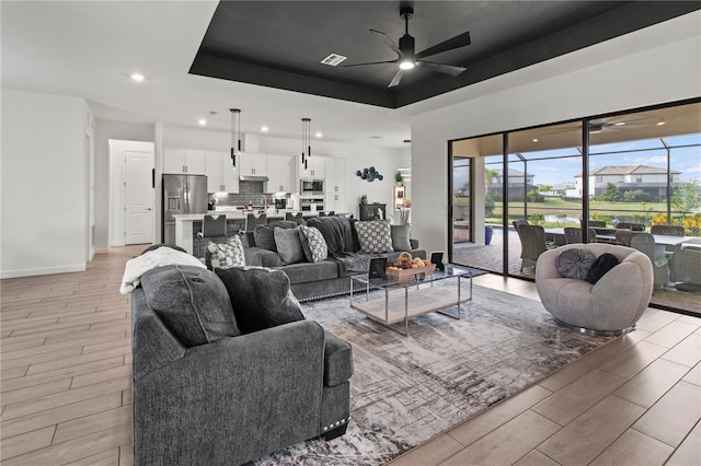 living room featuring a tray ceiling and ceiling fan