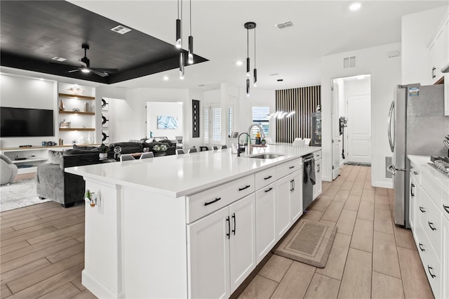 kitchen featuring white cabinetry, a center island with sink, ceiling fan, and decorative light fixtures