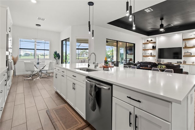 kitchen featuring white cabinets, an island with sink, stainless steel appliances, and decorative light fixtures