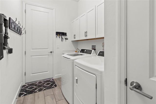 clothes washing area with cabinets and washer and clothes dryer