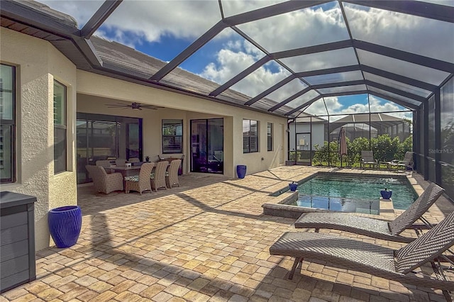 view of swimming pool with glass enclosure, ceiling fan, and a patio