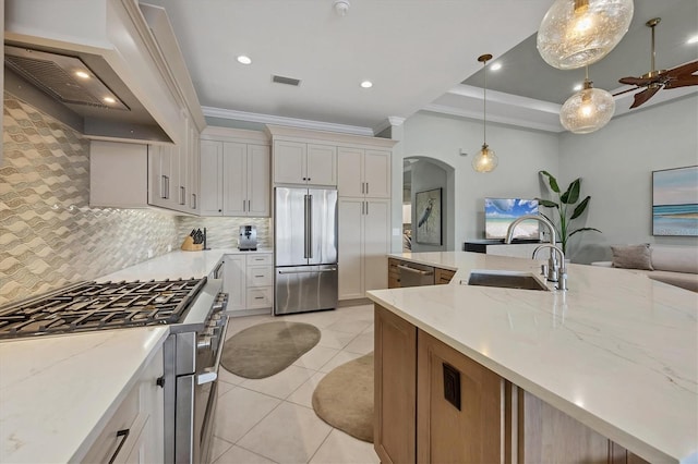 kitchen with appliances with stainless steel finishes, hanging light fixtures, light tile patterned floors, premium range hood, and white cabinets