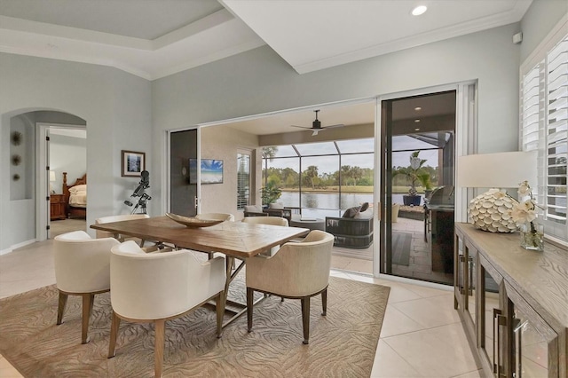 tiled dining area with ceiling fan, crown molding, and a water view