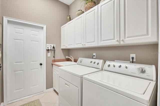 washroom featuring washer and dryer, sink, light tile patterned floors, and cabinets