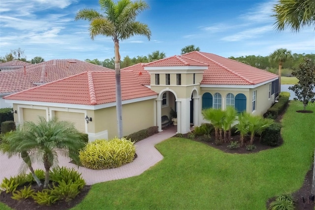 mediterranean / spanish house featuring a front yard and a garage