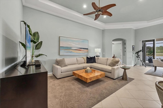 tiled living room featuring a high ceiling, a raised ceiling, and ceiling fan