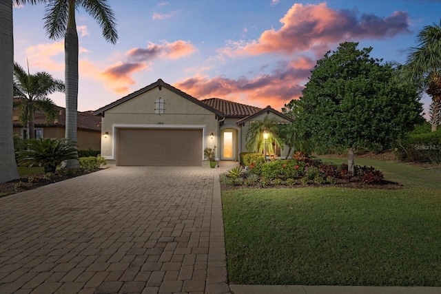 12606 Fontana Loop, Bradenton, FL 34211 - mediterranean / spanish house with an attached garage, a lawn, decorative driveway, and stucco siding