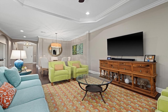 living room featuring a tray ceiling, hardwood / wood-style floors, a chandelier, and ornamental molding