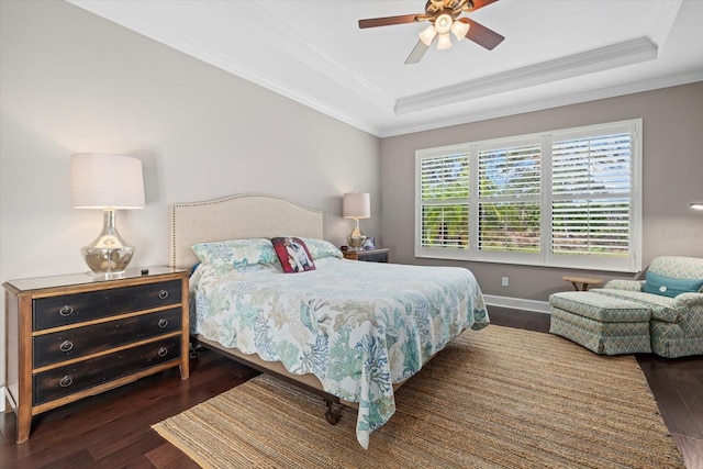 bedroom featuring dark hardwood / wood-style flooring, a raised ceiling, ceiling fan, and ornamental molding