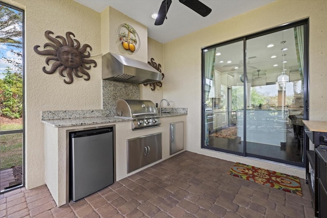 kitchen with decorative backsplash, wall chimney exhaust hood, ceiling fan, sink, and fridge