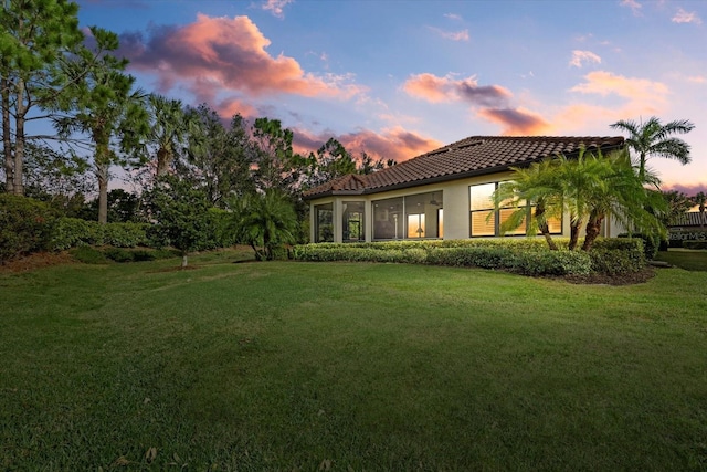 12606 Fontana Loop, Bradenton, FL 34211 - back of house at dusk featuring a yard, a tile roof, and stucco siding