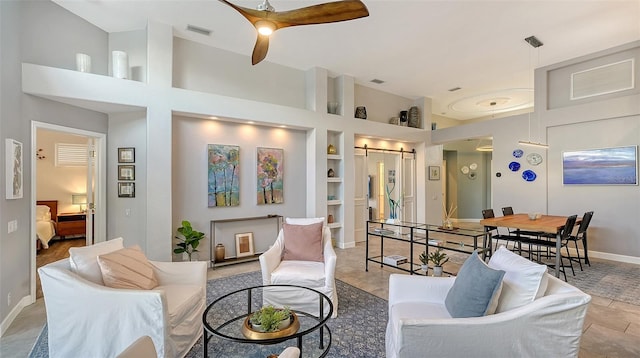 living room featuring a barn door, light tile patterned flooring, and built in shelves