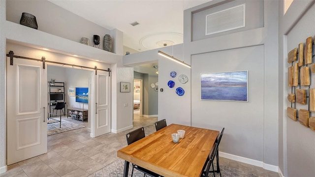 dining space featuring a barn door and light tile patterned floors