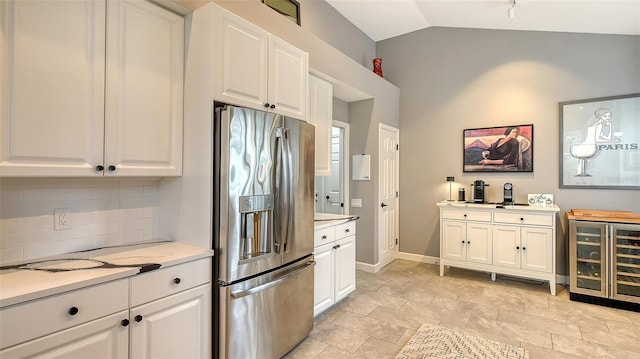 kitchen with lofted ceiling, white cabinets, and stainless steel refrigerator with ice dispenser