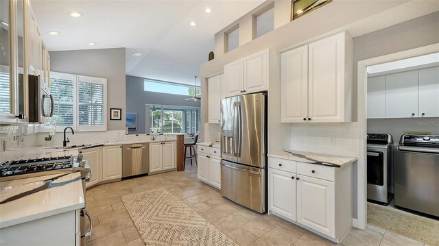 kitchen featuring white cabinetry, appliances with stainless steel finishes, decorative backsplash, lofted ceiling, and independent washer and dryer