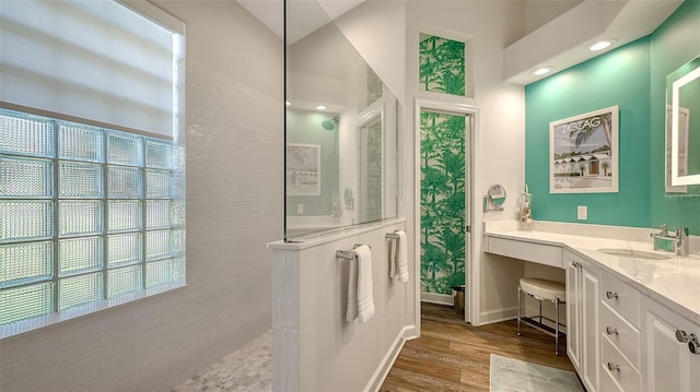 bathroom featuring wood-type flooring, tiled shower, and vanity