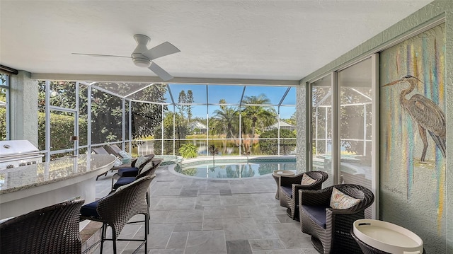 sunroom with ceiling fan, a wealth of natural light, and a water view