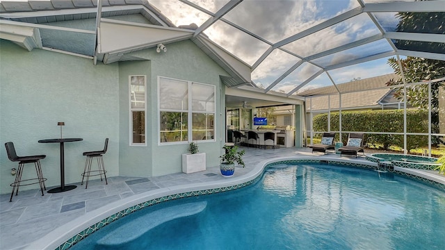 view of swimming pool featuring area for grilling, an in ground hot tub, exterior bar, a lanai, and a patio