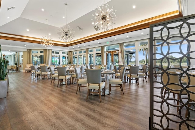 dining room with hardwood / wood-style floors, a tray ceiling, ornamental molding, and a notable chandelier