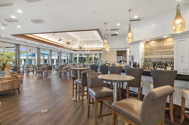 dining room featuring bar, dark hardwood / wood-style flooring, crown molding, and a tray ceiling