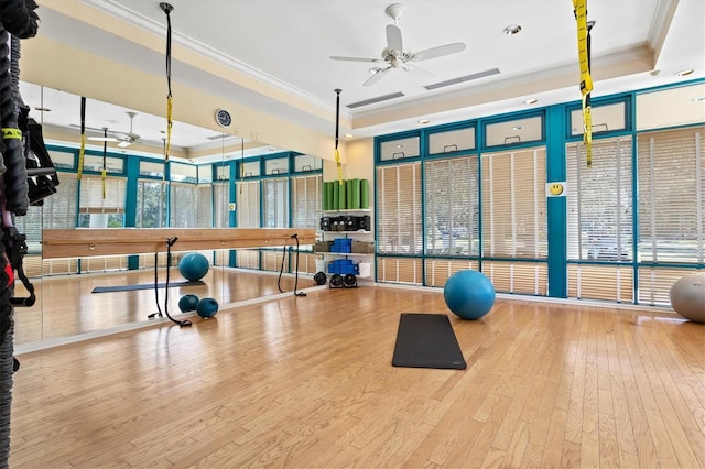 workout area with ceiling fan, hardwood / wood-style floors, a tray ceiling, and crown molding