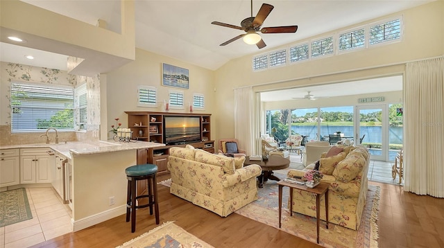 living room featuring sink, light wood-type flooring, a wealth of natural light, and ceiling fan