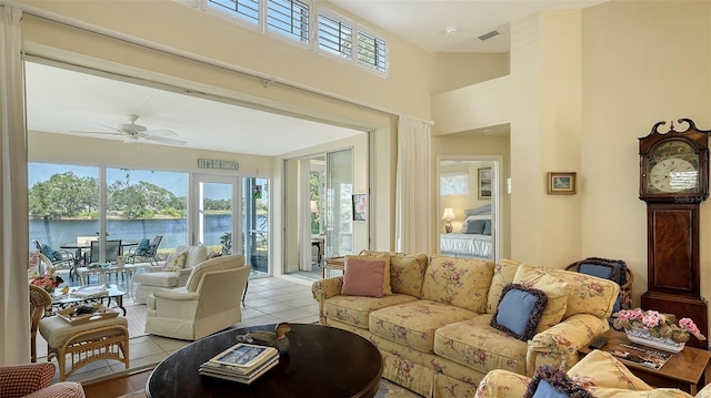 living room featuring light tile patterned floors, a water view, and ceiling fan