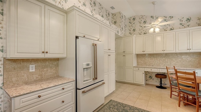 kitchen with lofted ceiling, ceiling fan, high end white fridge, light stone countertops, and light tile patterned floors