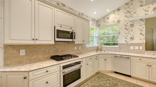 kitchen featuring sink, light stone countertops, stainless steel appliances, and light tile patterned floors