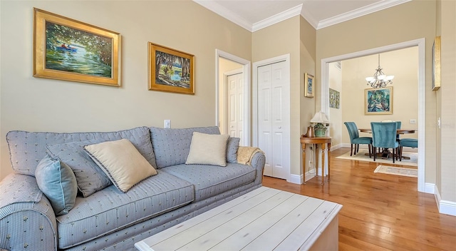 living room featuring light wood-type flooring, an inviting chandelier, and ornamental molding