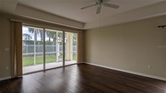 unfurnished room with dark hardwood / wood-style flooring, a raised ceiling, and ceiling fan