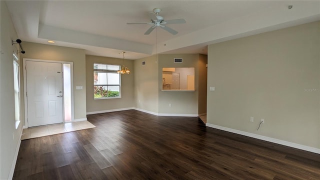 interior space featuring ceiling fan with notable chandelier, dark hardwood / wood-style flooring, and a raised ceiling