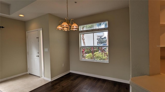 unfurnished dining area with hardwood / wood-style floors, a notable chandelier, and a wealth of natural light