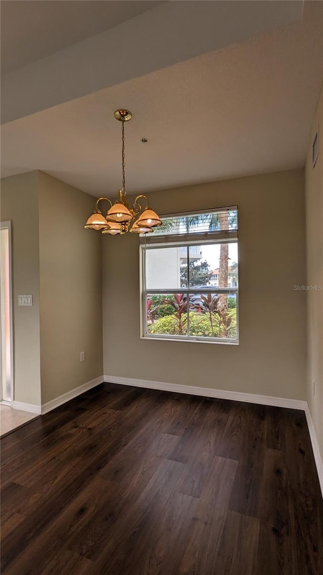 unfurnished dining area with dark hardwood / wood-style flooring and a chandelier