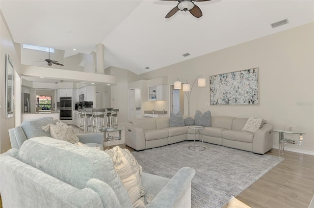 living room with ceiling fan, light hardwood / wood-style floors, and lofted ceiling