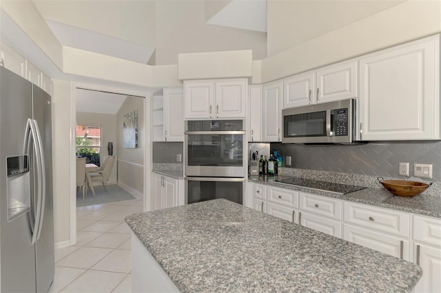 kitchen featuring white cabinets, light tile patterned floors, stainless steel appliances, and vaulted ceiling