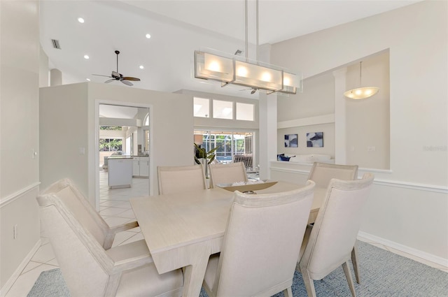 tiled dining area featuring ceiling fan and a high ceiling