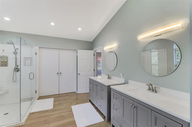 bathroom with vanity, hardwood / wood-style flooring, vaulted ceiling, and a shower with shower door