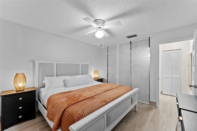 bedroom featuring ceiling fan, light hardwood / wood-style flooring, and a textured ceiling