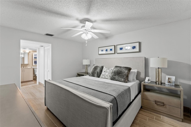 bedroom with ceiling fan, ensuite bath, and a textured ceiling