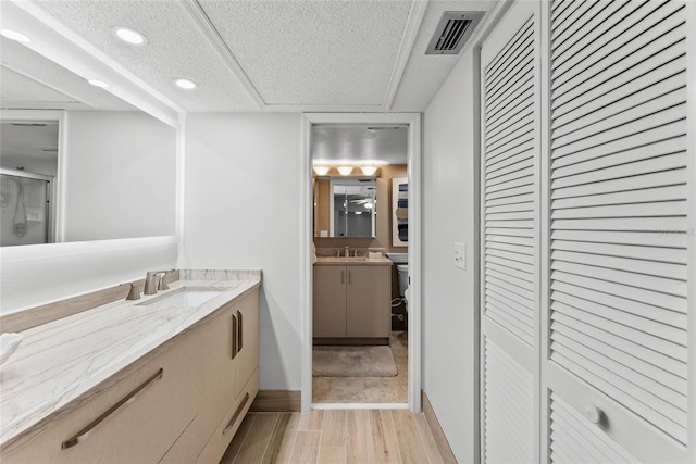 bathroom featuring hardwood / wood-style flooring, vanity, an enclosed shower, and a textured ceiling