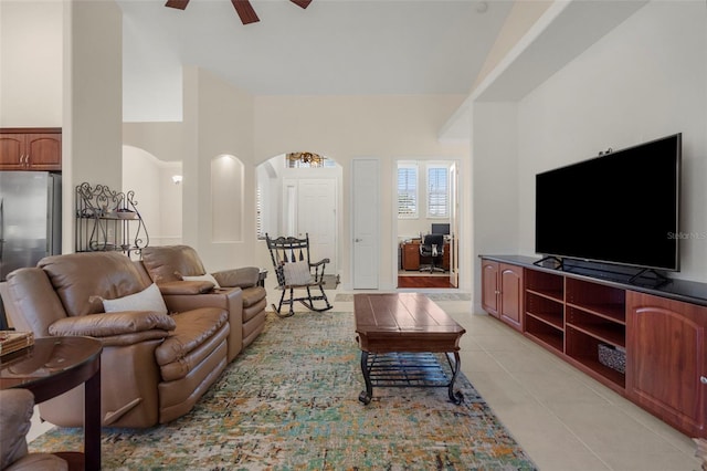 tiled living room with ceiling fan and high vaulted ceiling