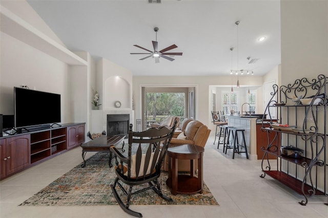 tiled living room with a tiled fireplace, sink, and ceiling fan