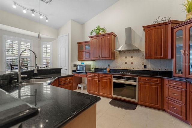 kitchen featuring sink, tasteful backsplash, decorative light fixtures, stainless steel appliances, and wall chimney range hood