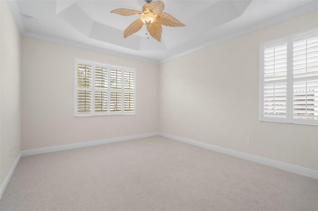 spare room with ceiling fan, light colored carpet, ornamental molding, and a tray ceiling