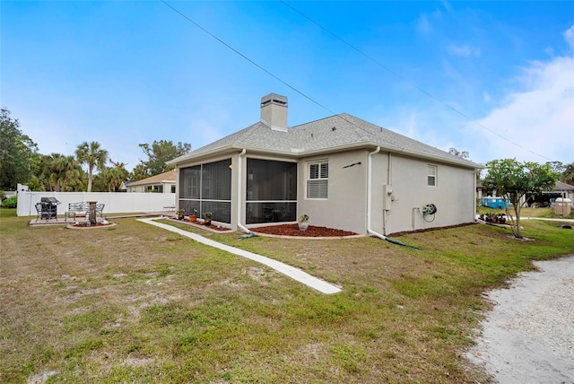 rear view of property featuring a lawn, a sunroom, and a patio area